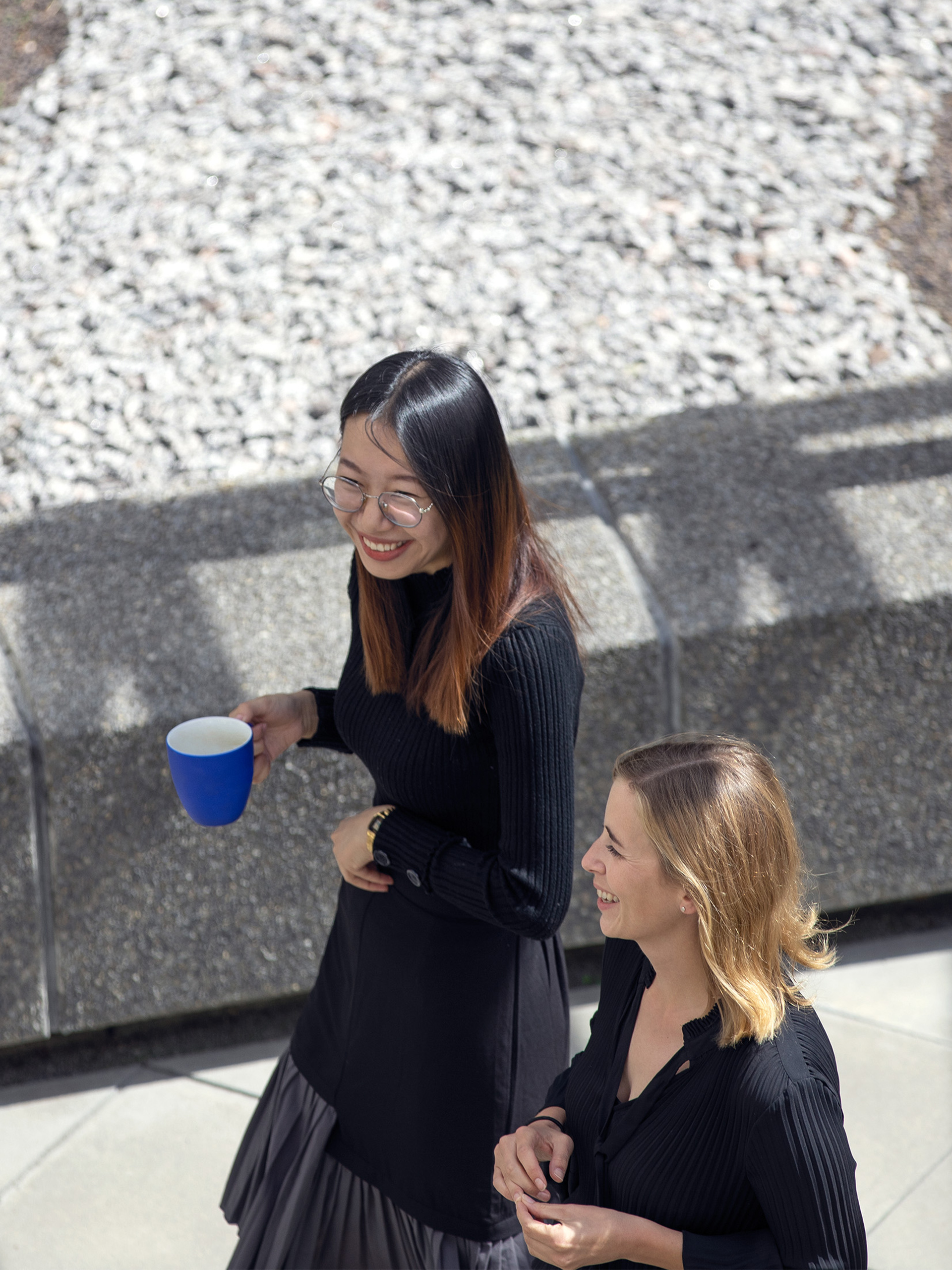 women walking with coffe mug laughing